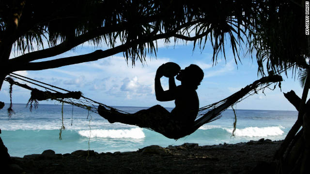 File photo of a man drinking coconut milk as he watches tides pound the coast of Funafuti Atoll, home to nearly half of Tuvalu's entire population.