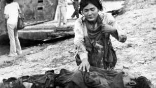 A woman cries beside a dead body in Phnom Penh after fall of the city on 17 April, 1975.
