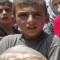 A Syrian boy carries bags of bread after as people queue up outside a bakery in the northern town of Aldana near Syria&#39;s second largest city Aleppo, on July 31, 2012. 