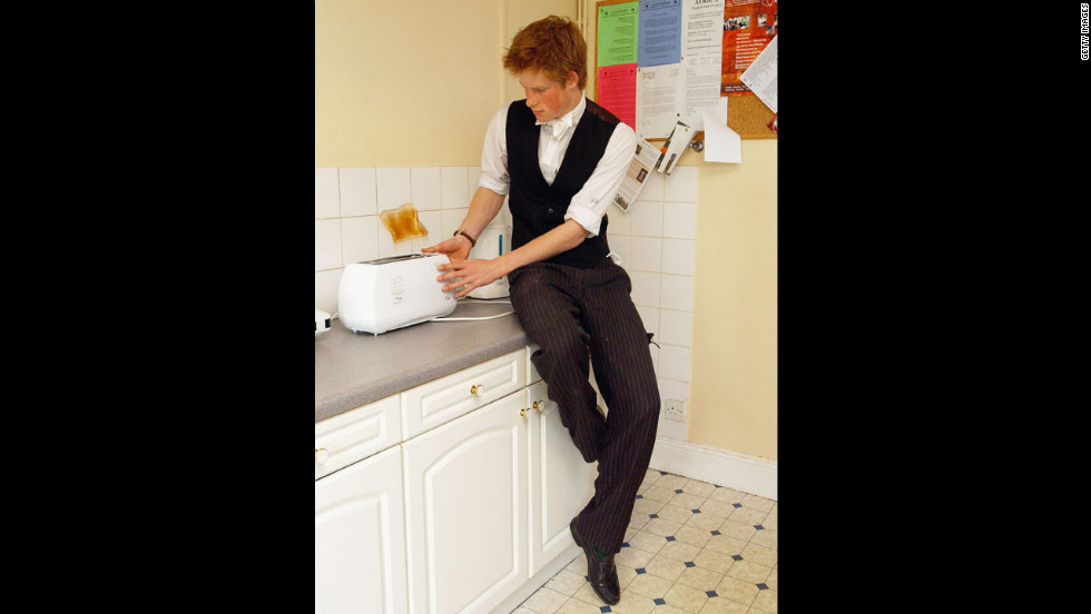 The youngest son of the Prince of Wales, Prince Harry makes a slice of toast in his house kitchen situated in the house library, which is the preserve of the senior House prefects, in March 2003 at Eton College.