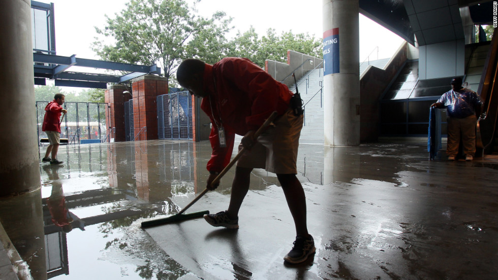Grounds crew workers clear water during a rain delay on Saturday.