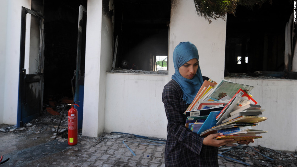 A woman collects books from a classroom in the American school in Tunis on Saturday.