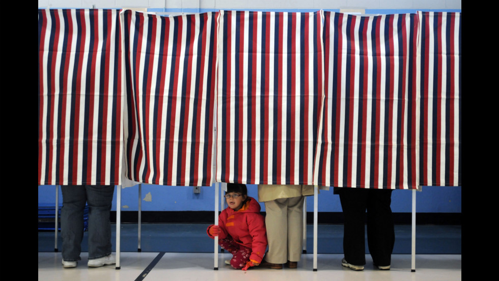 A young girl peered out from under a voting booth as her mother cast a ballot at the Bishop Leo O'Neil Youth Center in Manchester, New Hampshire.