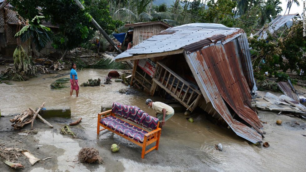 Residents clean their sofa next to their damaged house in New Bataan township on December 5.