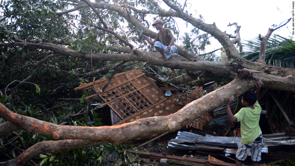 A resident cuts branches of a toppled tree in Montevista, Philippines, on December 6. It fell onto his house at the height of Typhoon Bopha. 