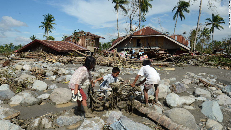 Children retrieve a bicycle among boulders near destroyed houses in New Bataan on December 6.