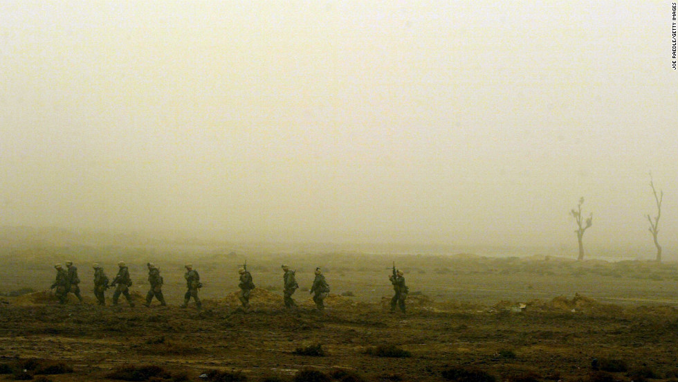 Marines walk single-file through the desolate landscape in Nasiriyah on March 26, 2003. As night falls on the city, the troops are on alert for a counterattack.