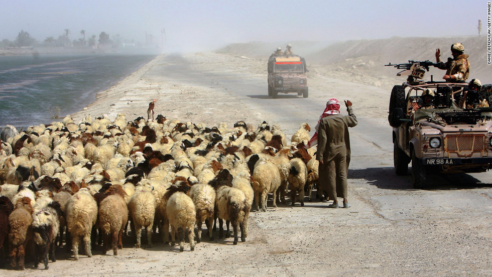 A British Royal Air Force gunner waves to a goat herder during a patrol of northern Basra province on July 26, 2006.