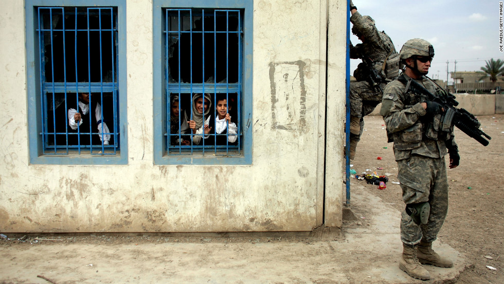 Iraqi children watch U.S. Army soldiers climb to the roof of their school to get a high vantage point in Baghdad on April 15, 2007.