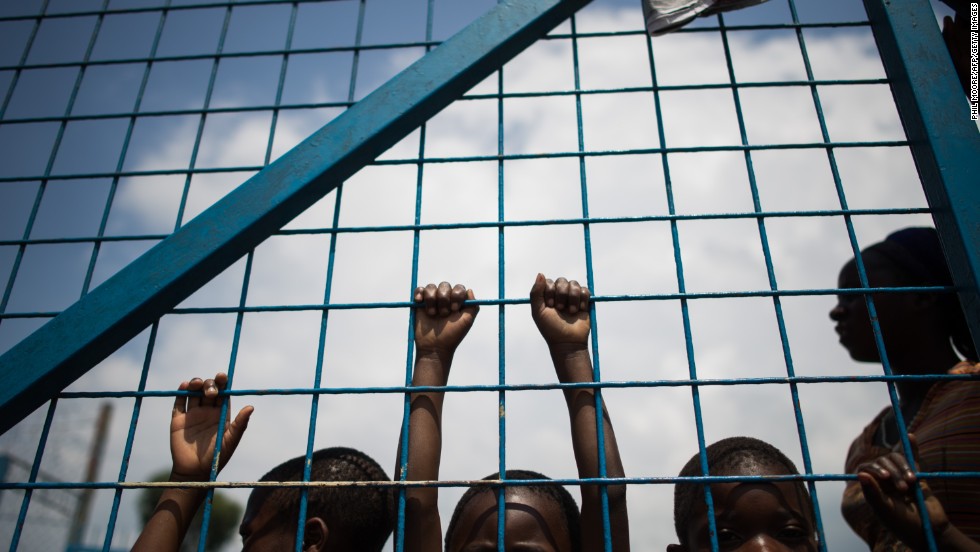 Displaced children stand against the gate of a religious organization on the outskirts of Goma.