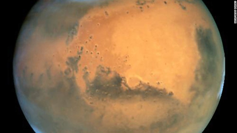 IN SPACE - JUNE 26: NASA's Earth-orbiting Hubble Space Telescope took this picture June 26, 2003 of Mars. Mars was approximately 43 million miles (68 million km) from Earth, the closest Mars has ever been to Earth since 1988. Frosty white water ice clouds and swirling orange dust storms above a vivid rusty landscape reveal Mars as a dynamic planet in this sharpest view ever obtained by an Earth-based telescope. Hubble can see details as small as 10 miles (16 km) across. Especially striking is the large amount of seasonal dust storm activity seen in this image. One large storm system is churning high above the northern polar cap (Top) and a smaller dust storm cloud can be seen nearby. (Photo by NASA/Getty Images)