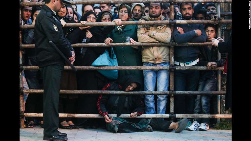 Koukab sits on the ground amongst the crowd before her son was brought out from the prison.