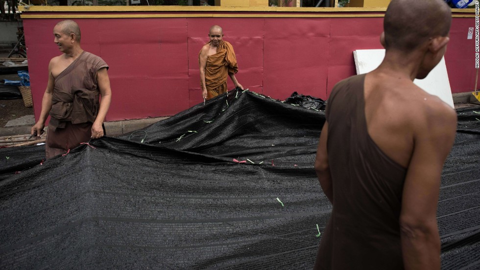 Buddhist monks help dismantle a shade net at an anti-government camp occupied for months in Bangkok on May 23.