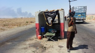 An ISIS militant stands guard at a checkpoint captured from the Iraqi Army outside Beiji refinery, 155 miles north of Baghdad, on June 19.