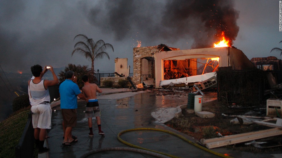 Residents photograph the burning ruins of their home, which was destroyed in a wildfire in Carlsbad, California, in May. Drought conditions fueled several wildfires across the state, fire officials said.