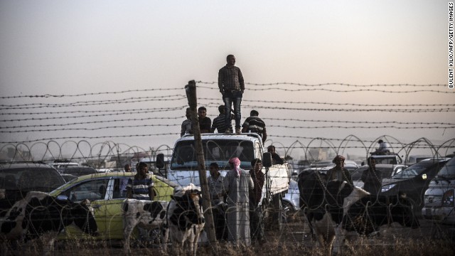 Syrian Kurds fleeing ISIS militants wait behind a fence in Suruc on Sunday, September 21.