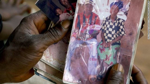 Etienne Ouamouno holds a photo of his wife and son Emile. Researchers think the boy was the outbreak&#39;s first victim.