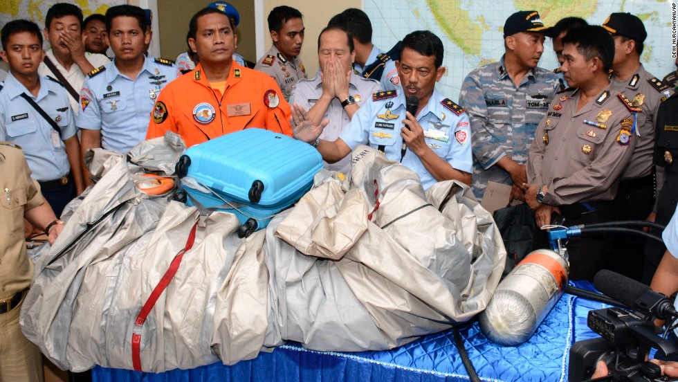 Indonesian air force personnel show debris, including a suitcase, that was found floating near the site where the AirAsia flight disappeared.