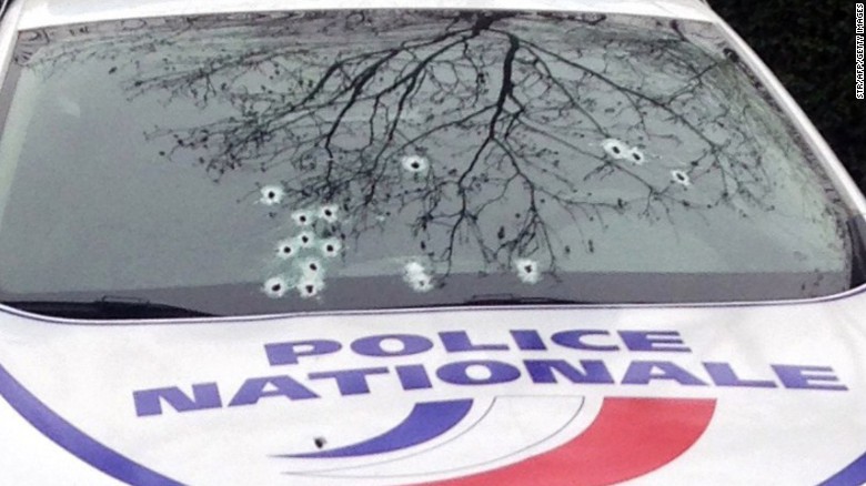A police car sits riddled with bullets.