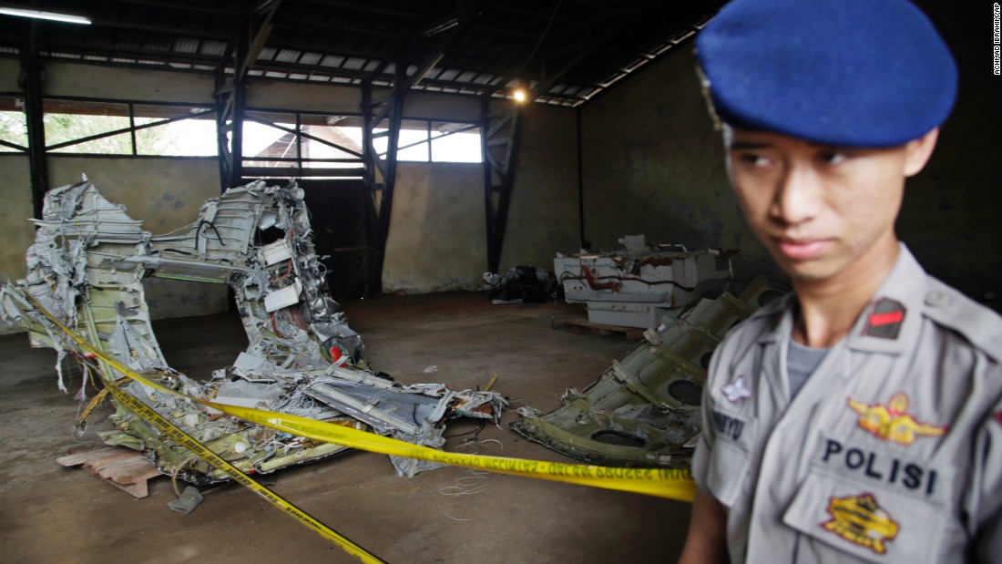 A police officer stands guard near pieces of wreckage from AirAsia Flight QZ8501 at a warehouse in Pangkalan Bun, Indonesia, on Monday, January 19.