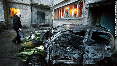 A man stands next to his car in Donetsk on Sunday, February 1, after it was destroyed by shelling.