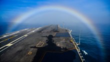 A rainbow forms over the bow of the Nimitz-class aircraft carrier USS John C. Stennis as the ship steams in the Pacific Ocean on February 3, 2015.