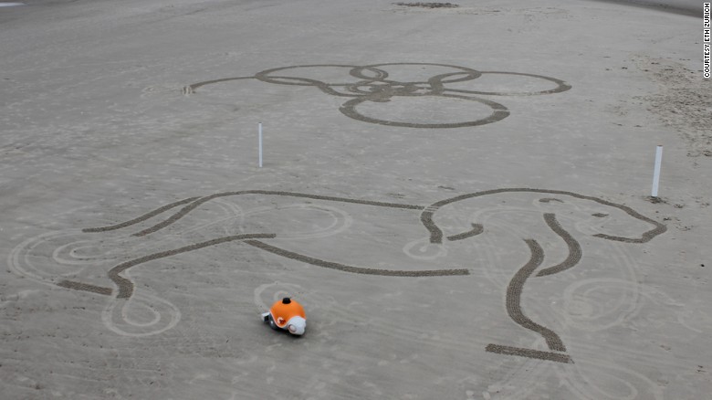 The robot's bulbous balloon wheels allow it to traverse the entire sandy canvas without leaving tire tracks.