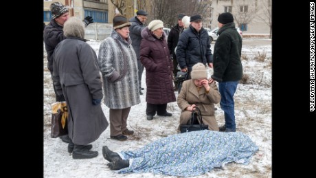 People stand beside the body of a woman killed during shelling in Kramatorsk, Ukraine, on Tuesday, February 10.