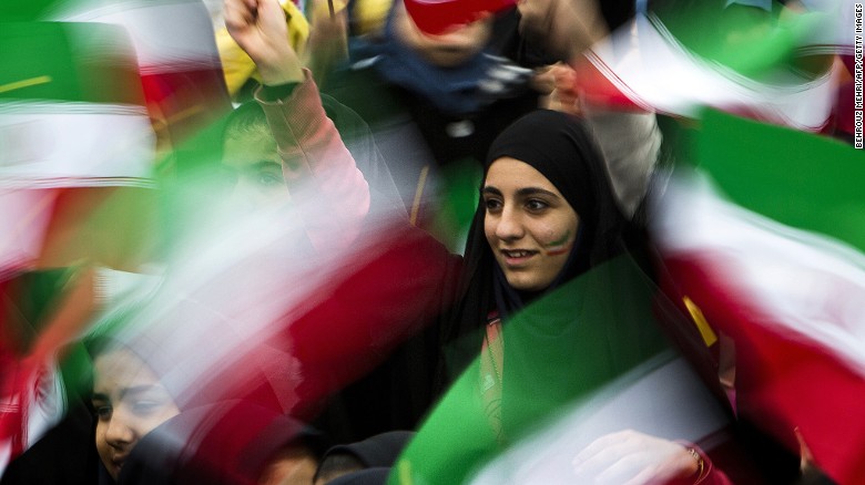 Iranian schoolgirls wave their national flag during the 36th anniversary of the Islamic revolution in Tehran