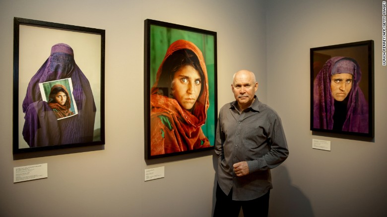 Photographer Steve McCurry poses next to his photos of the &quot;Afghan Girl&quot; named Sharbat Gula at the opening of the &quot;Overwhelmed by Life&quot; exhibition at the Museum for Art and Trade in Hamburg, Germany in 2013.