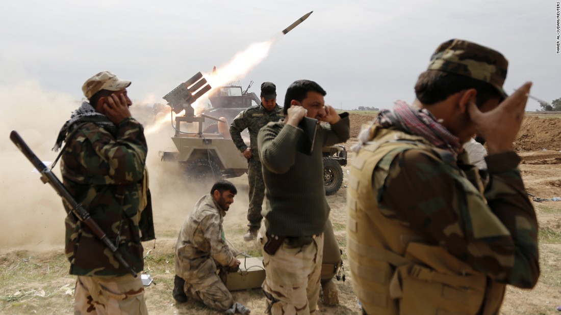 Iraqi Shiite fighters cover their ears as a rocket is launched during a clash with ISIS militants in the town of Al-Alam, Iraq, on Monday, March 9.