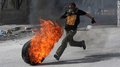 A Palestinian protester kicks a flaming tire towards Israeli soldiers (unseen) during clashes near the Israeli Qalandia checkpoint between the West Bank city of Ramallah and Jerusalem on November 14, 2014.