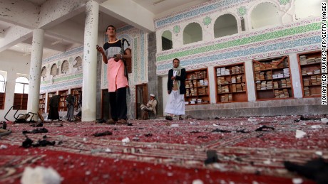 Armed men inspect damage after an explosion at the Al Badr mosque in Sanaa on Friday, March 20.