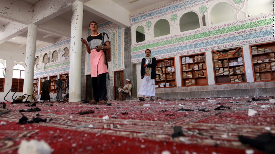 Armed men inspect damage after an explosion at the Al Badr mosque in Sanaa on Friday, March 20.
