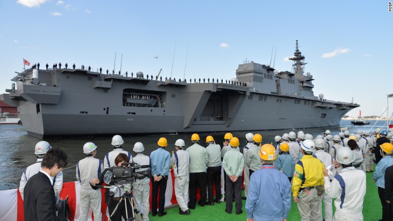 Workers look on at Japan&#39;s newest -- and biggest -- warship, the Izumo, moored in Yokosuka, Kanagawa prefecture.