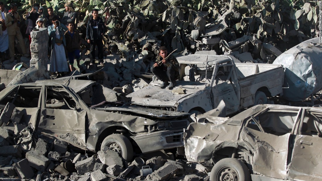 People gathered around burned vehicles after Saudi-led airstrikes against the Houthis near Sanaa Airport on March 26.
