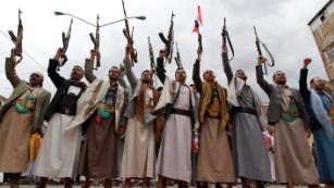 Houthi fighters raise their weapons