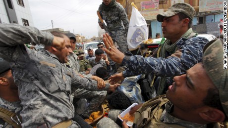 A member of Iraq's security forces beats a suspected ISIS member who was captured in Tikrit on Wednesday, April 1.