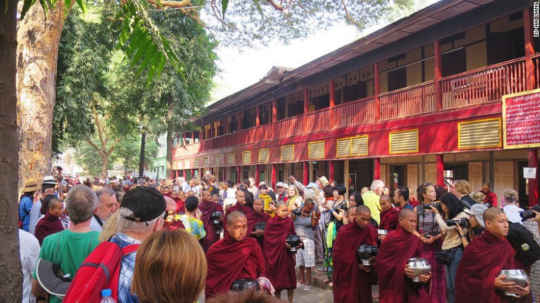 Around 10 a.m. each day, tourists gather on the side of the road at Mahagandhayon Monastic Institution in Amarapura, Myanmar, waiting for the appearance of the monastery&#39;s monks.