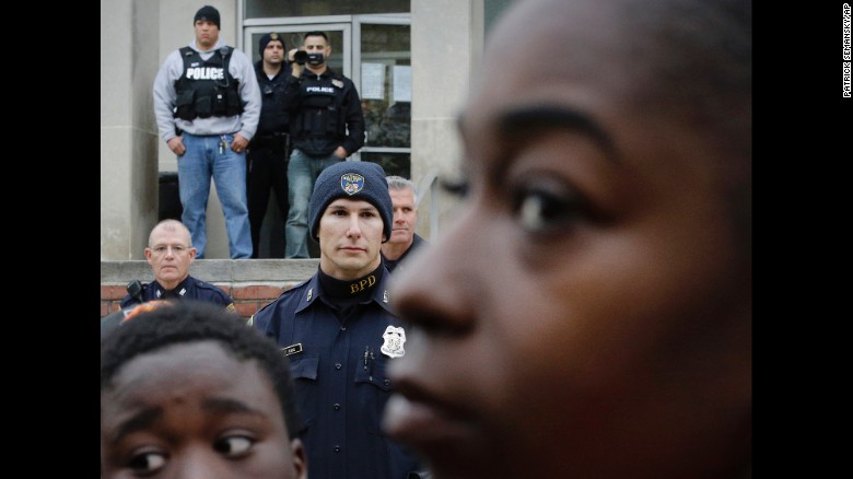 A police officer films protesters from the steps of the Western District station on April 23.