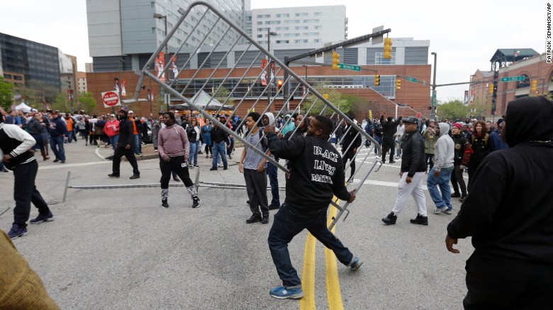 A protester throws a barricade at a bar near Oriole Park at Camden Yards after a rally on April 25.