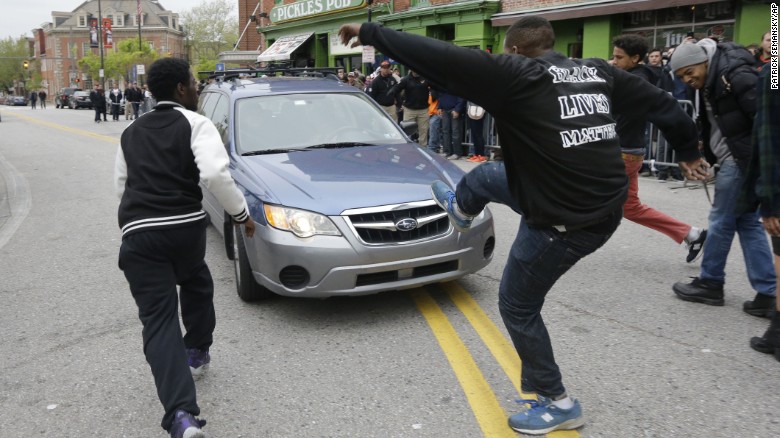 Protesters chase after a car as it drives in reverse after the rally on April 25.
