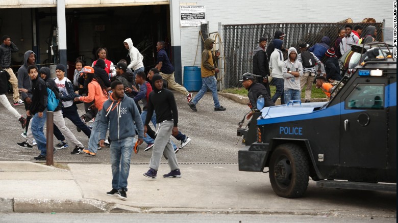 A police vehicle chases protesters away in a parking lot along Reisterstown Road near Mondawmin Mall on April 27.