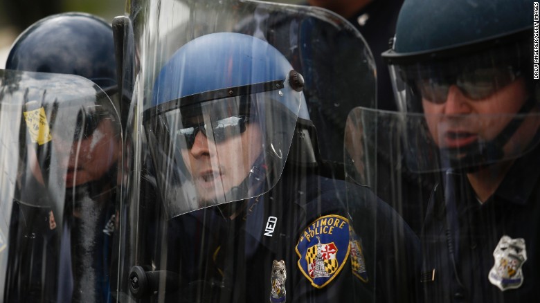 Baltimore police officers in riot gear look toward protesters near Mondawmin Mall on April 27.