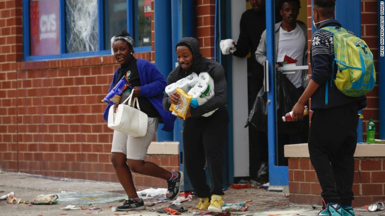 People carry goods out of a CVS pharmacy near Pennsylvania and North avenues on April 27.