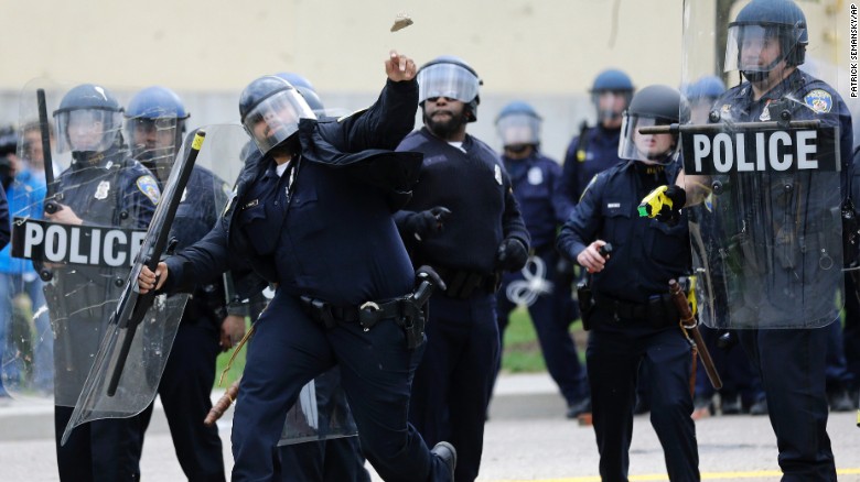 A police officer throws an object at protesters on April 27.