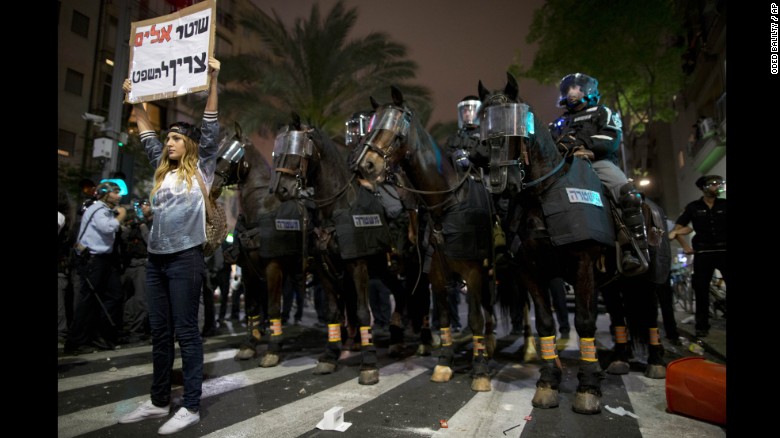 An Israeli protester holds a sign reading &quot;violent policemen should be sentenced&quot; during clashes between protesters and Israeli riot police in Tel Aviv on Sunday, May 3. The protest was sparked after video emerged showing what appeared to be two police officers beating a uniformed Israeli soldier of Ethiopian origin.