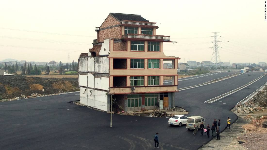 A half-demolished apartment building stands isolated in the middle of a newly-built road on November 22, 2012. Luo Baogen, 67, a duck farmer, and his 65-year-old wife refused to move out from their home in eastern China&#39;s Zhejiang province, waging a four-year long battle with the local government over a compensation plan. 