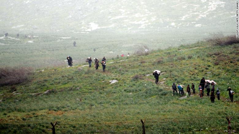 Syrian refugees walk across a field in Syria before crossing into Turkey on March 14, 2012.