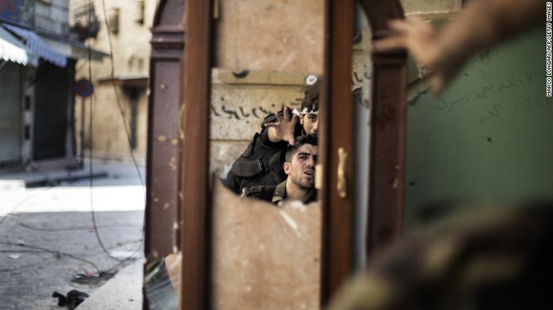 Free Syrian Army fighters are reflected in a mirror they use to see a Syrian Army post only 50 meters away in Aleppo on September 16, 2012.